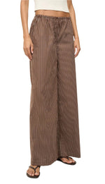 Someone is wearing Staud Bonfire Pant in brown striped cotton poplin wide-leg style with black flip-flops, and a hint of a white top shows at the waist.