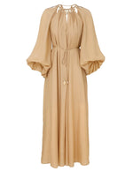 The Mahon Maxi Dress by Zimmermann is a long beige dress with billowy sleeves, a gathered neckline, and a gold-accented tie waist.