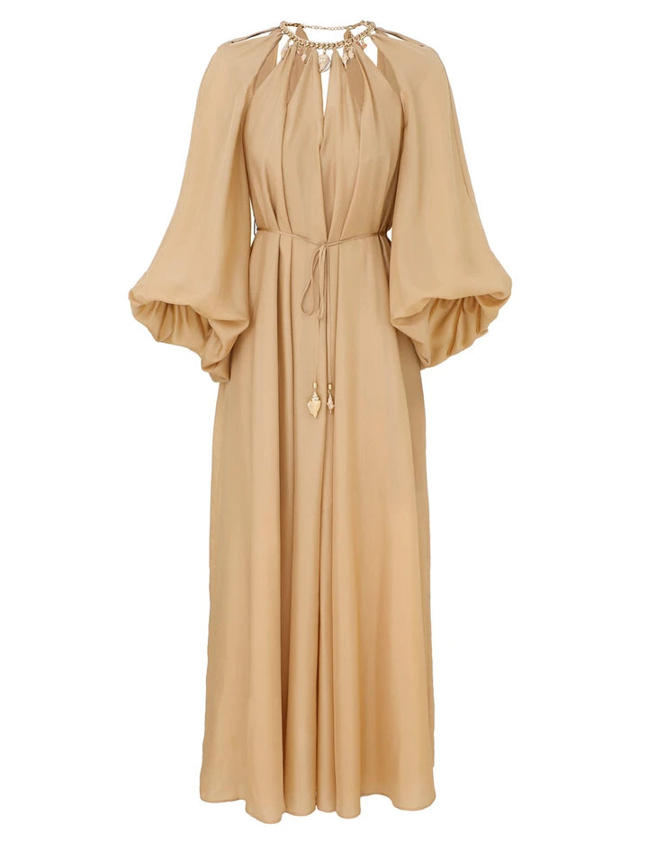 The Mahon Maxi Dress by Zimmermann is a long beige dress with billowy sleeves, a gathered neckline, and a gold-accented tie waist.