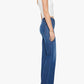 A woman stands sideways against a plain white background wearing the Mother Kick It high-rise straight-leg jean—crafted from recycled stretch denim with a 32-inch inseam—paired with a white sleeveless top and teal open-toe heels.