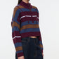 A woman wearing the Staud Hampton Cashmere Sweater—a cropped, long-sleeve, striped style with a half-zip collar—paired with high-waisted dark jeans, stands against a plain white background.