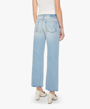 A person wearing The Dodger Flood slouchy, light blue denim jeans by Mother, styled with white heels and standing with their back to the camera against a plain white background.