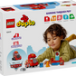 A child plays with the LEGO® DUPLO® Mack at the Race set from Legos - Toyhouse; the box shows toy pieces and highlights benefits like building confidence and sparking imagination.