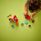 A child assembles LEGO® DUPLO® Mack at the Race blocks from Legos - Toyhouse on a green surface, with pieces and a toy wrench scattered nearby.