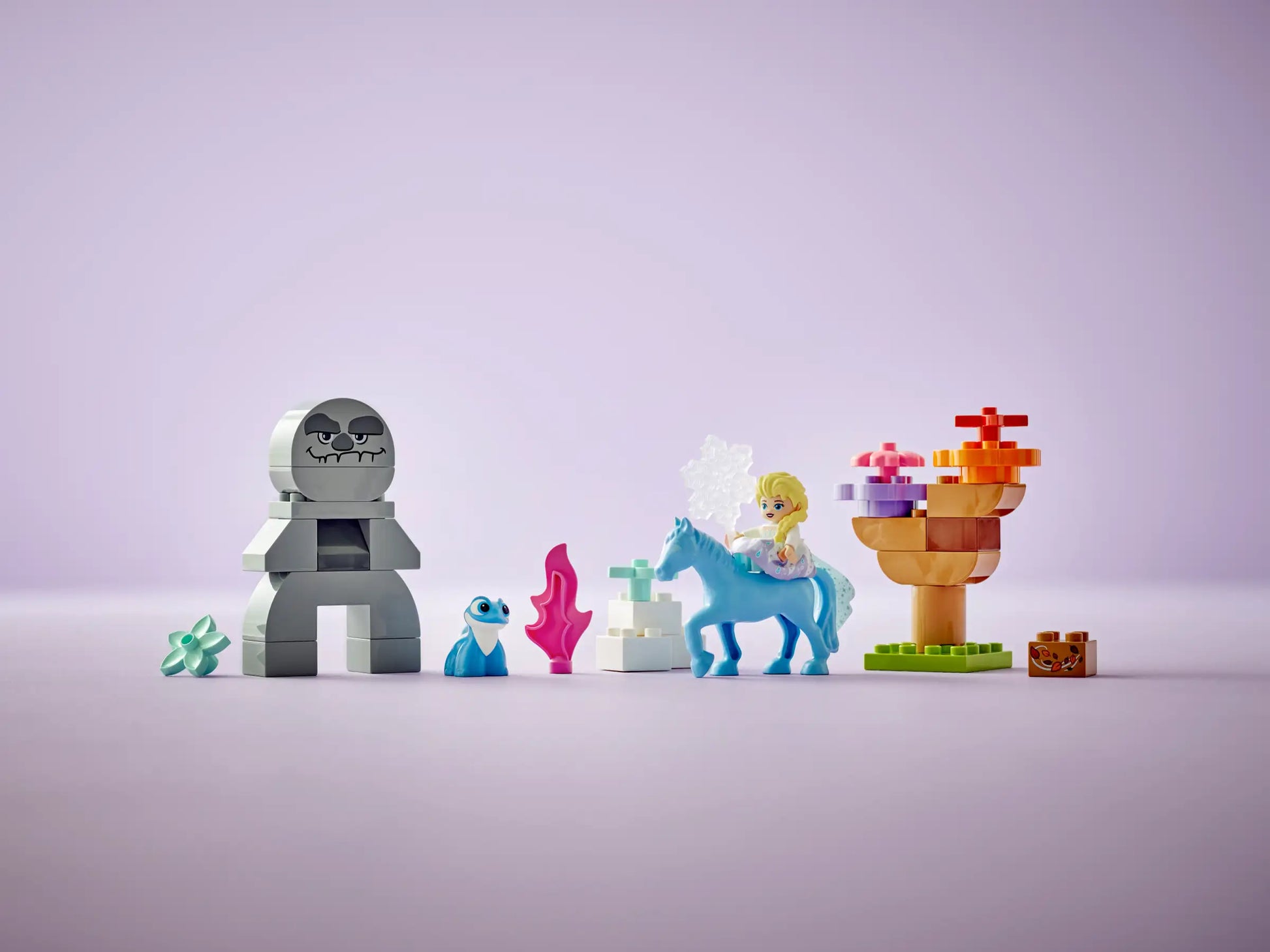 The LEGO® DUPLO® Elsa & Bruni in the Enchanted Forest set by Legos - Toyhouse features Elsa, Bruni, a girl on a blue horse, a gray creature, tree, and accessories; all displayed on a light purple background.