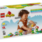 A child plays with the LEGO® DUPLO® Creative Garden & Flowers by Legos - Toyhouse, assembling colorful flower-shaped pieces. The box displays the LEGO DUPLO logo and features for boosting creativity and fine motor skills.