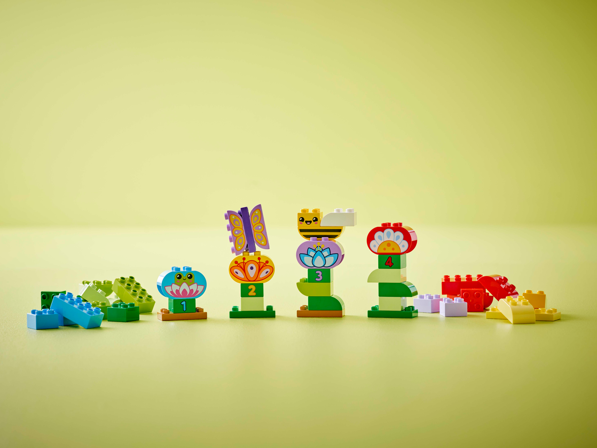 Legos - Toyhouse LEGO® DUPLO® Creative Garden & Flowers features colorful blocks built into flower and animal shapes numbered 1 to 4, making it an ideal preschool learning toy on a bright yellow surface.