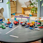 A round black table displays Legos - Toyhouse LEGO® DUPLO® F1® Team Race Cars & Drivers, with a living room and green plants in the background.