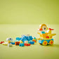 The LEGO® DUPLO® 3in1 Animals on Wheels by Legos - Toyhouse includes colorful blocks and animal figures with wheels—such as a yellow duck—plus blue, white, and orange pieces, all displayed on a light green surface with a green background.