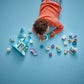 A child in a red sweater plays on a blue floor with Legos - Toyhouse pieces, including character figures and a toy house from the LEGO® DUPLO® Anna and Elsa's Frozen Castle Party set.