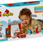 A young child plays with the LEGO® DUPLO® McQueen's Visit to Doc's Garage set from Legos - Toyhouse, which features a buildable race car, garage pieces, and themed accessories.