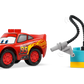 The LEGO® DUPLO® McQueen's Visit to Doc's Garage by Legos - Toyhouse features a toy car with number 95 and a smiling face, plus red, blue, and yellow building blocks and accessories—great for any toddler playset.