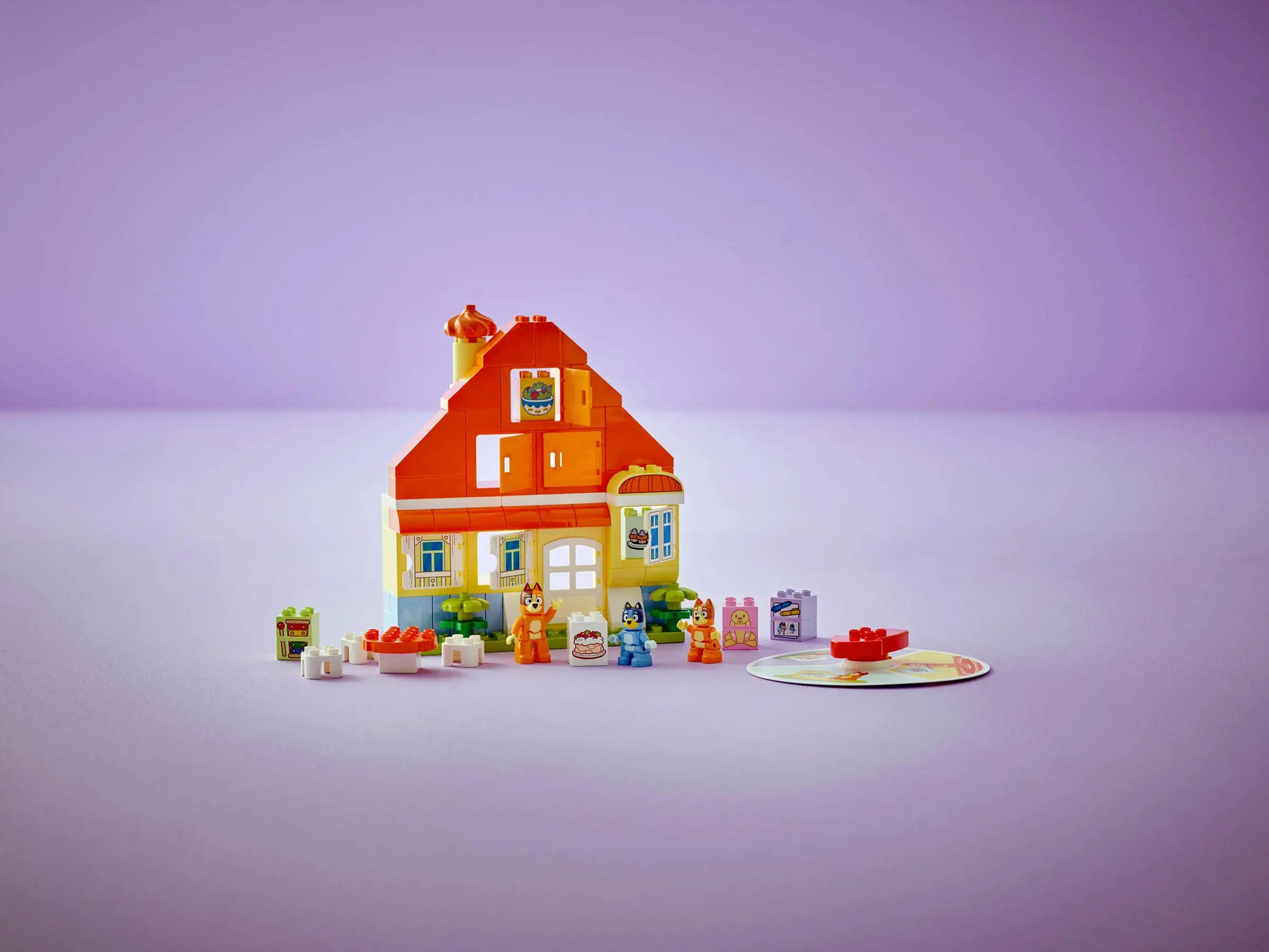 The LEGO® DUPLO® Bluey's Family House with Memory Game by Legos - Toyhouse features colorful interlocking bricks, mini figures, and accessories against a purple background, creating an interactive play scene for imaginative fun.