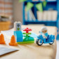 A LEGO® DUPLO® Blue Police Motorcycle by Legos - Toyhouse features a minifigure in a white helmet, traffic cones, flower, and small traffic light—ideal as an emergency vehicle or toddler learning toy.