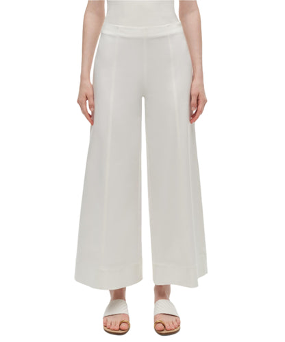 A person wearing Simkhai's Kallin Cropped Wide Leg Pant in heavy cotton and white sandals stands against a plain background.