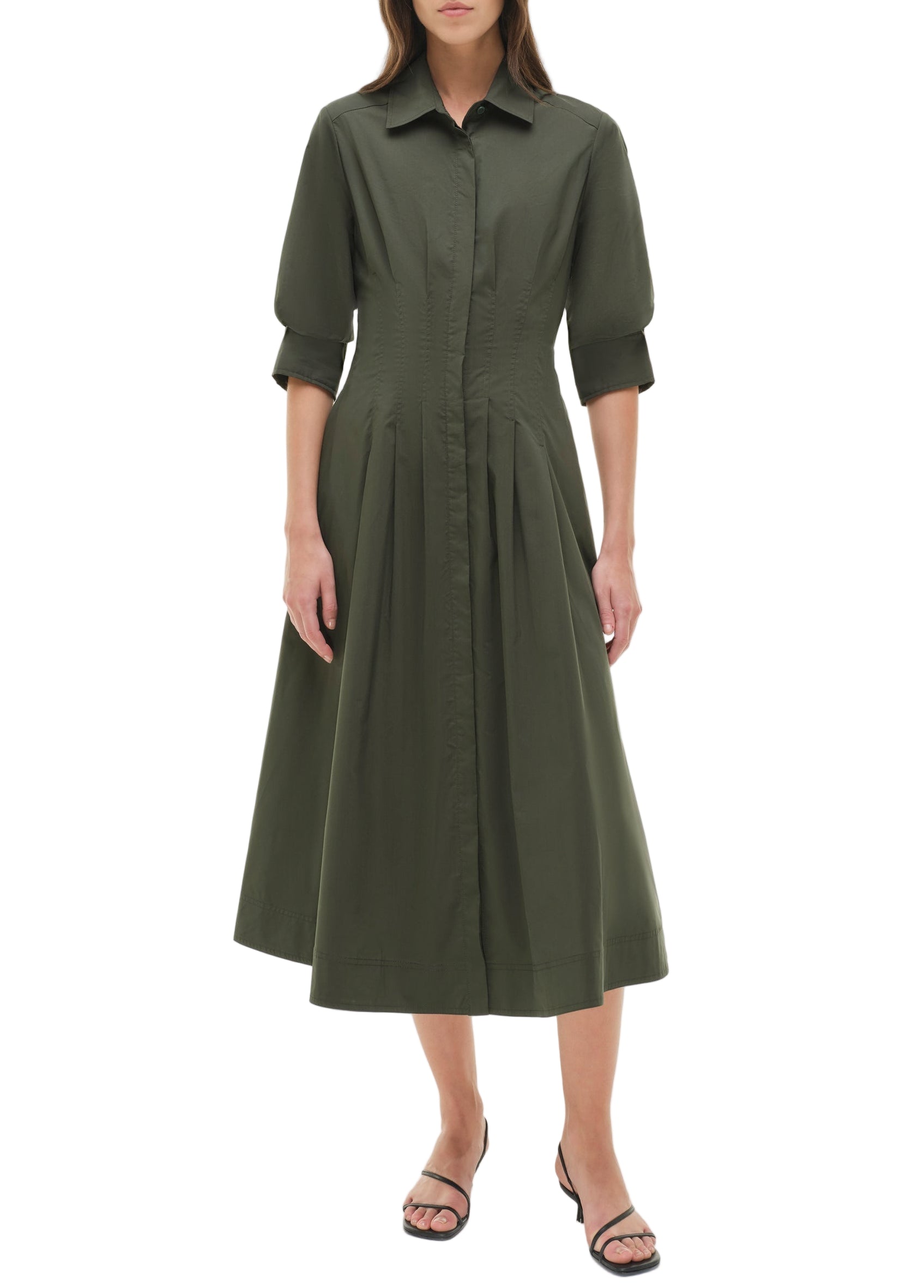 A woman wears the Simkhai Signature Jazz Dress—an olive green, collared, button-down cotton poplin midi with elbow-length sleeves—and black sandals, standing against a plain white background.