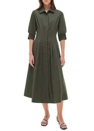 A woman wears the Simkhai Signature Jazz Dress—an olive green, collared, button-down cotton poplin midi with elbow-length sleeves—and black sandals, standing against a plain white background.