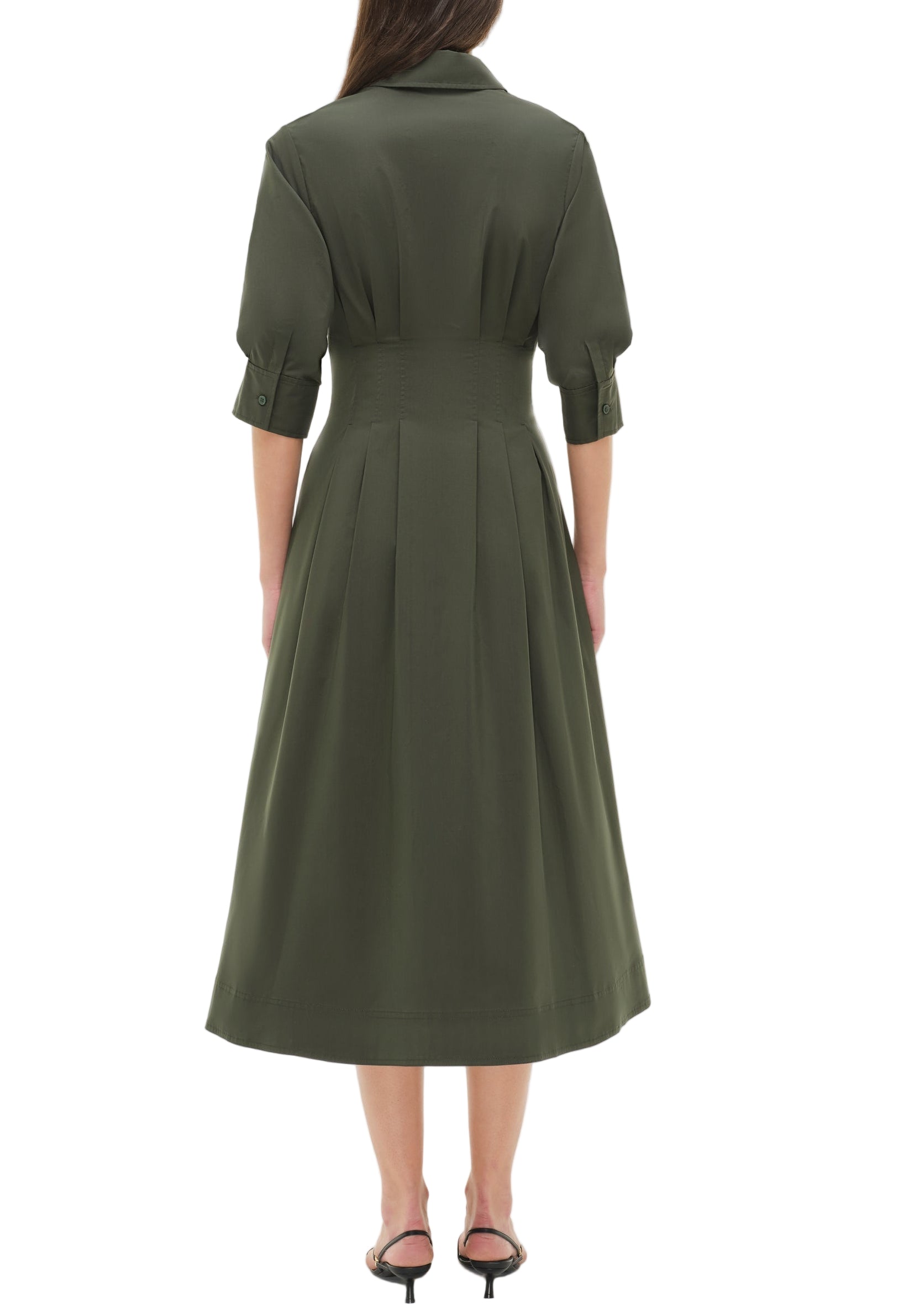 A woman stands facing away, wearing the Simkhai Signature Jazz Dress with three-quarter sleeves and black heeled sandals.