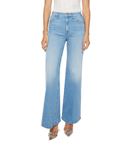 A model showcases Mother’s The Hustler Roller Sneak high-waisted, light blue stretch denim flare jeans with a white top, standing against a plain background; only the lower torso and legs are visible.