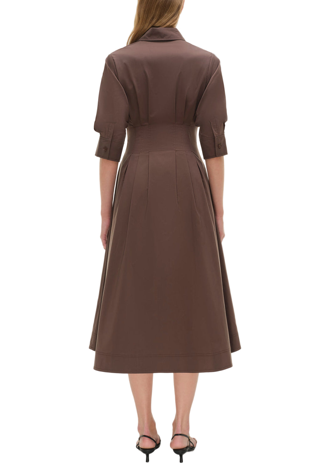 A woman faces away, wearing the Simkhai Signature Jazz Dress—a brown pintuck midi with an A-line silhouette and three-quarter sleeves—paired with black heeled sandals.