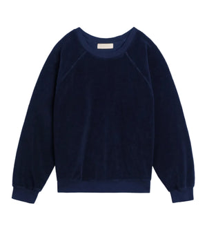 The Suzie Kondi Samos Sweatshirt is a navy blue long-sleeve crewneck with comfy sleeves, ribbed cuffs and hem, and a relaxed fit, shown flat on a white background—ideal for travel or lounging.