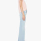 A person standing in profile wears a light pink short-sleeved shirt, The Hustler Roller Skimp Fray jeans by Mother in a light blue high-rise wide-leg style, and black sandals against a plain white background.