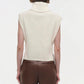 A model is seen from the back wearing the Simkhai Maple Top, a sleeveless turtleneck in cream, paired with brown leather pants. The look emphasizes a structured silhouette and minimalist style against a plain background.