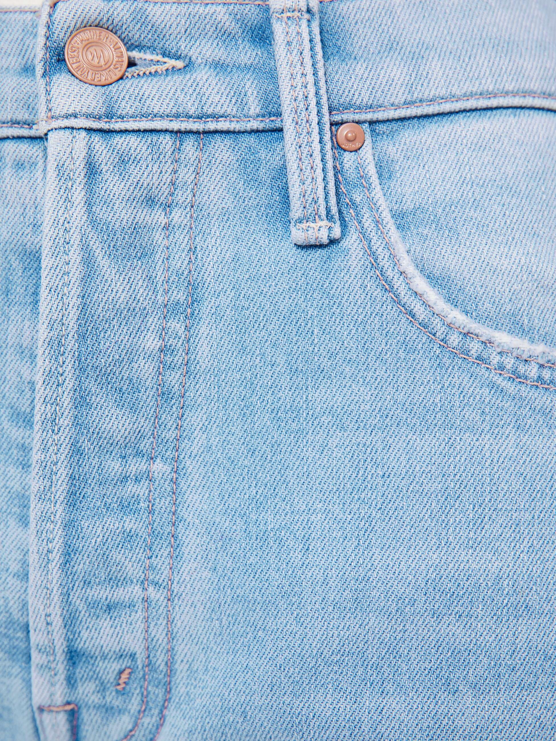 Close-up of the front section of Mother’s The Tripper Flood Fray jeans in light blue denim, focusing on the button, waistband, and pocket stitching.