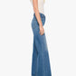 A woman stands sideways against a plain white background wearing heeled sandals, a white sleeveless top, and the Tomcat Roller Sneak high-waisted wide-leg jeans by Mother in a vintage-inspired blue wash.
