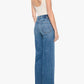 A woman stands in profile against a white background, showcasing the Mother Tomcat Roller Sneak jeans—a high-waisted, wide-leg silhouette crafted from vintage-inspired SUPERIOR denim—paired with a white sleeveless bodysuit and high heels, her back partially visible.