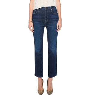 A person wears the Mother Tripper Flood dark blue, high-rise flare jeans crafted from a stretch cotton blend, paired with a light top and pointed-toe heels, standing against a white background.