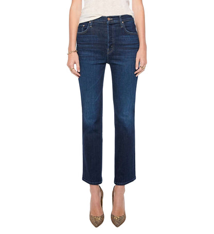 A person wears the Mother Tripper Flood dark blue, high-rise flare jeans crafted from a stretch cotton blend, paired with a light top and pointed-toe heels, standing against a white background.