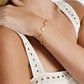 A person in a sleeveless white eyelet top showcases the Anabel Aram Butterfly Coin Charm Bracelet, featuring elegant butterfly and leaf-shaped charms on their wrist.