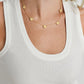A woman wears a white ribbed tank top and an Anabel Aram Butterfly Coin Station Necklace, featuring evenly spaced round pendants.