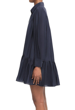 Person wearing a navy blue Simkhai Viola Dress with a ruffled hem and button-down front, standing sideways.