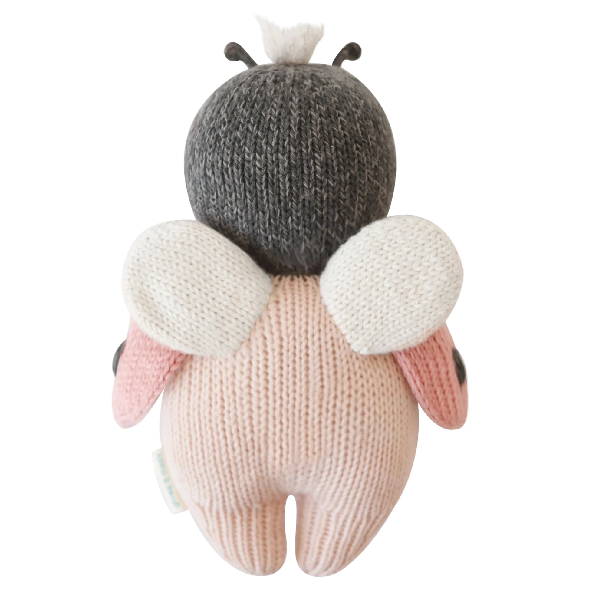 The Baby Ladybug by Cuddle + Kind is a collectible, heirloom-quality knitted plush toy featuring a gray head, white wings, pink body, and black antennae—perfect for fans of hand-knit baby animals.