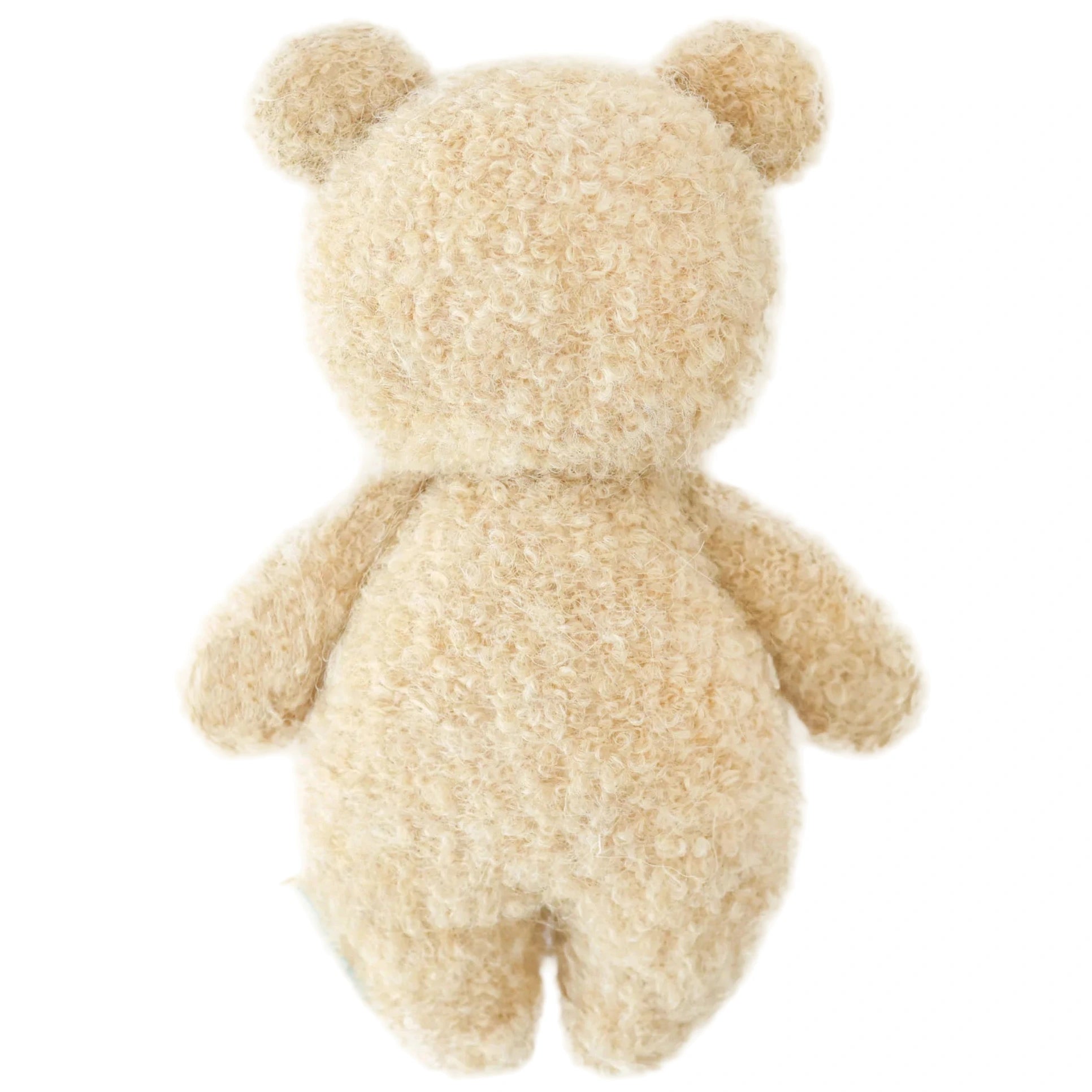The Cuddle + Kind Baby Boucle Bear - Honey is shown from the back, highlighting its curly beige texture and soft Peruvian cotton yarn with visible head, ears, arms, and legs against a white background.
