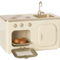 The Maileg Miniature Kitchen is a small, cream-colored playset featuring a metal oven, stove, sink, and three baked buns on a tray inside the open oven.