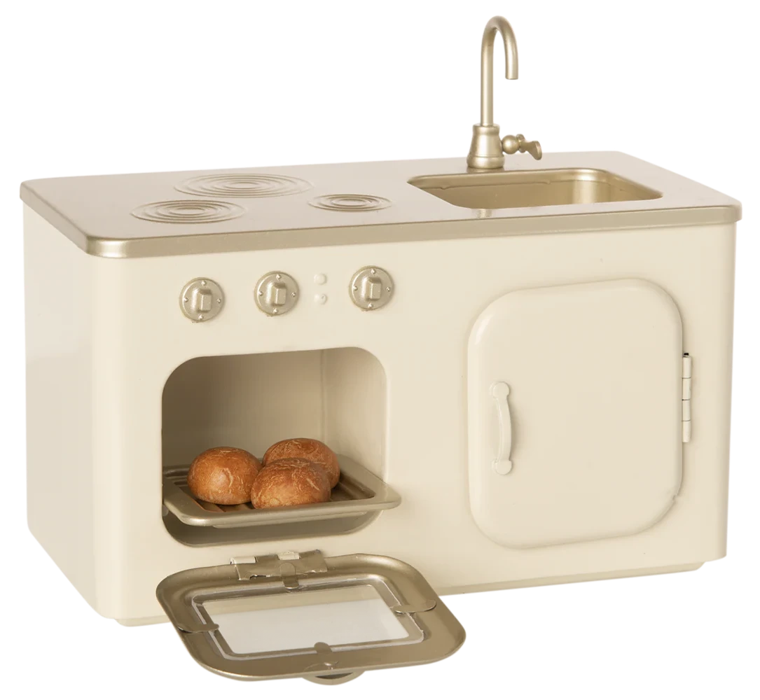 The Maileg Miniature Kitchen is a small, cream-colored playset featuring a metal oven, stove, sink, and three baked buns on a tray inside the open oven.