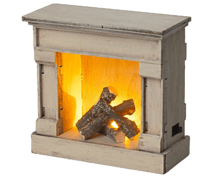 The Maileg Fireplace in Off-White by Maileg is a small, decorative piece with a rustic design, complete with logs and a simulated glowing fire effect. Its vintage painted look adds charm, making it a standout addition to your home.