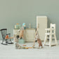 Three micro bunnies play in a vintage kitchen—one mops, another holds a sponge, and the third stands by the Maileg High Chair - Micro among charming miniature toy furniture.