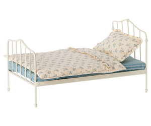 The Maileg Miniature Bed, Mini - Blue, is a white metal vintage-style dollhouse bed with blue-and-beige floral bedding (pillow and comforter) on a blue striped mattress, shown isolated on a white background.
