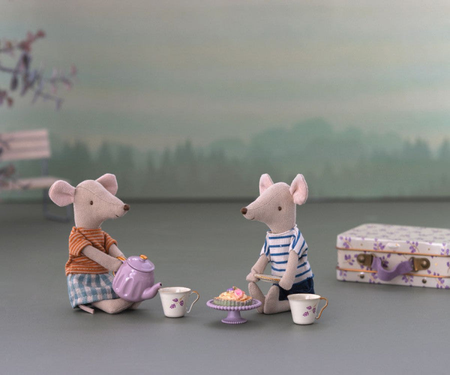 Two Maileg Purple Madelaine Afternoon Treat mice sitting at a table with a tea set and a small suitcase.