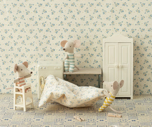 Three Maileg toy mice in striped clothes sit in a miniature room with floral wallpaper, a white wardrobe, a bench, a washing machine, mouse-sized furniture, a blanket on the floor, and an Off White High Chair for mice.