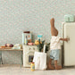 A Maileg stuffed rabbit in a striped shirt and shorts opens the Maileg Miniature Fridge in a vintage-style miniature kitchen filled with various food items and appliances.