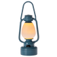 The Maileg Blue Vintage Lantern - Mouse is a charming blue metal lantern with a glass center, glowing with a warm yellow light. Standing upright against a plain white background, it’s perfect for bringing farmhouse charm to your décor or illuminating your next camping adventure.