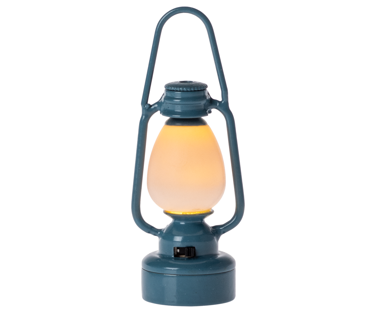 The Maileg Blue Vintage Lantern - Mouse is a charming blue metal lantern with a glass center, glowing with a warm yellow light. Standing upright against a plain white background, it’s perfect for bringing farmhouse charm to your décor or illuminating your next camping adventure.