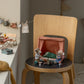 The Maileg Garden Set, Mouse features toy mice with camping gear by a small tent on a chair, another mouse at a picnic table, and doll clothes hanging on a string in this cozy outdoor scene.