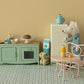 A Maileg Big Pale Pink Cafe Set - Mouse features a toy bear beside a miniature fridge and table, with orange juice, a croissant, and a cup, all styled in the charming Mouse Hole Farmhouse kitchen setting with delightful food accessories.