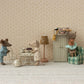 In a charming dollhouse scene by Maileg, three toy mice enjoy the "Cafe Set, Mouse, Small - Off White": one serves tea to a little sister, another lounges by the table, and the third stands proudly on the couch amid delightful furniture.